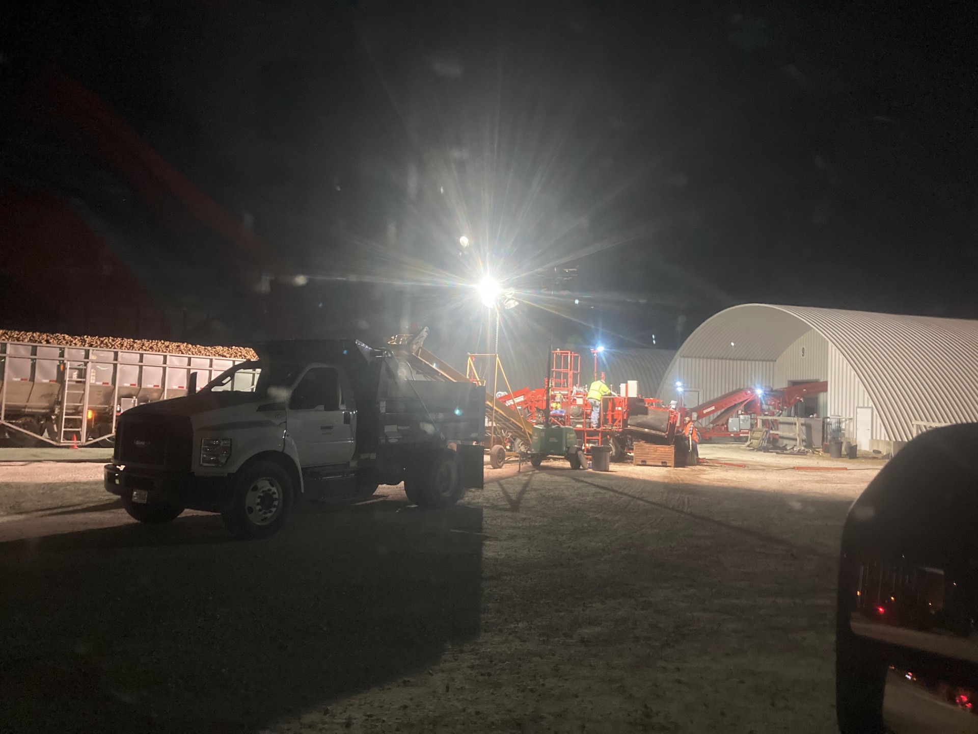 Harvested potatoes being brought into a storage facility at night.